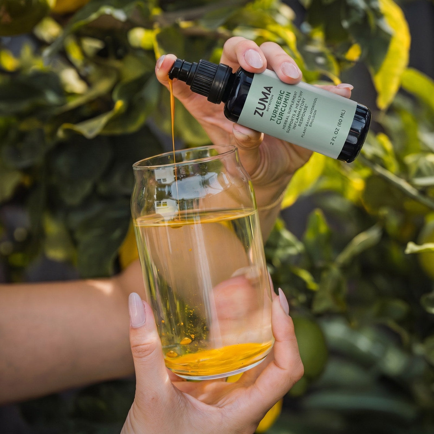 Pouring Liposomal Turmeric Curcumin into a glass of water