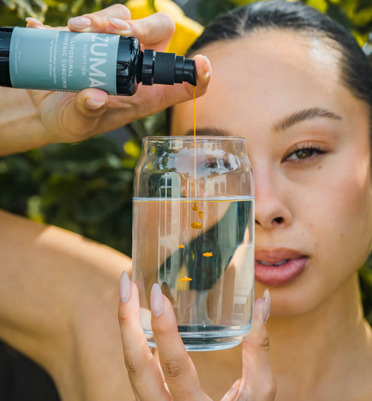 Female Model dispensing Zuma Nutrition Curcumin into water glass