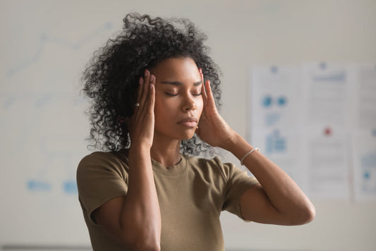Exhausted woman rubbing her temples, feeling unwell — common herx reaction symptoms