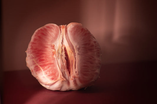 Peeled grapefruit divided in half on a red table, dark lighting