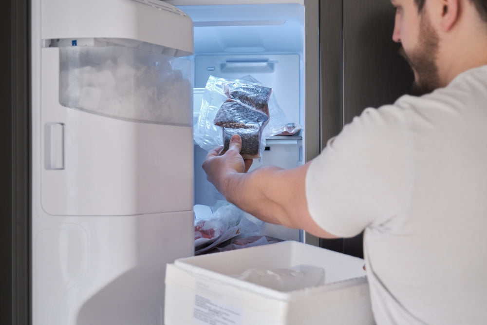 Young latin man put it in the freeze his weekly delivery of fish