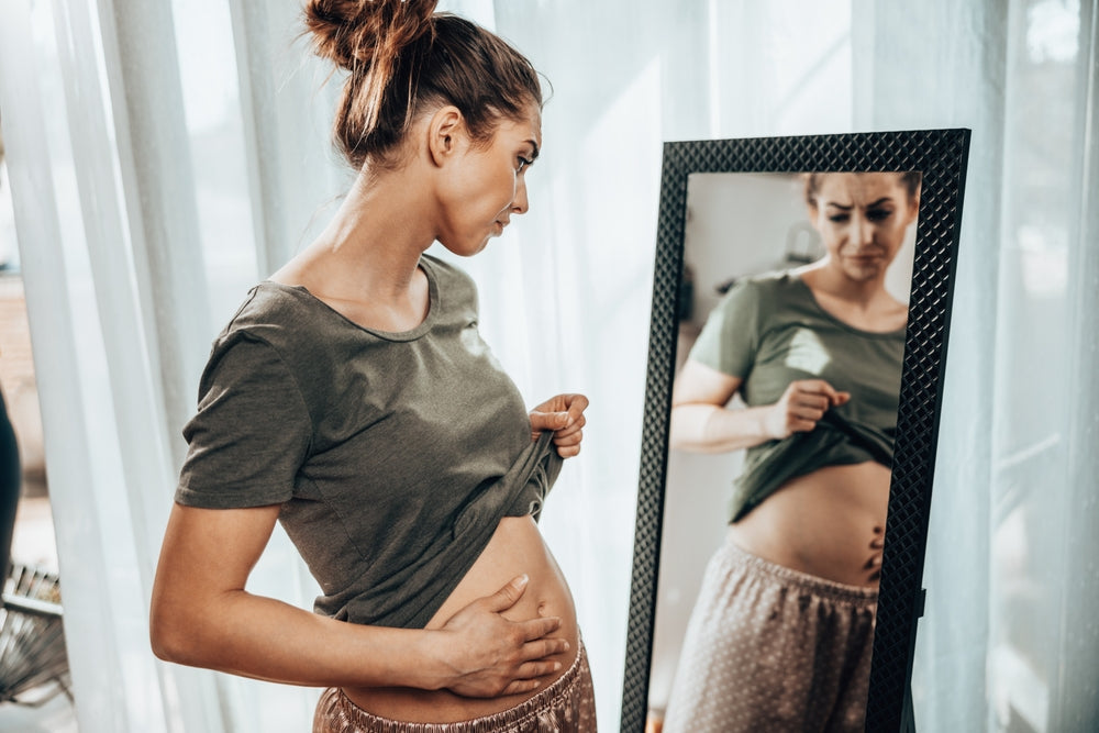 Unhappy woman standing in front of a mirror 