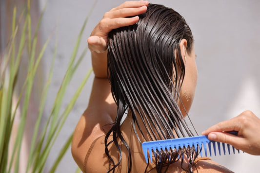 Woman combing hair outside with blue comb