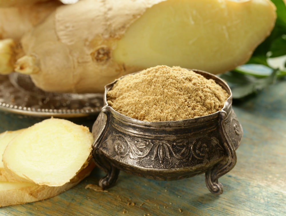 Board with ginger and ginger powder on wooden background