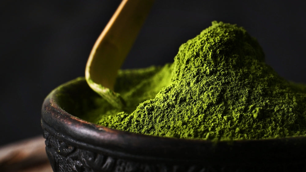 Matcha green tea powder hill in a bowl with spoon close up view