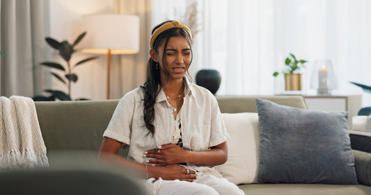 Stomach pain, woman and digestion illness on couch at home