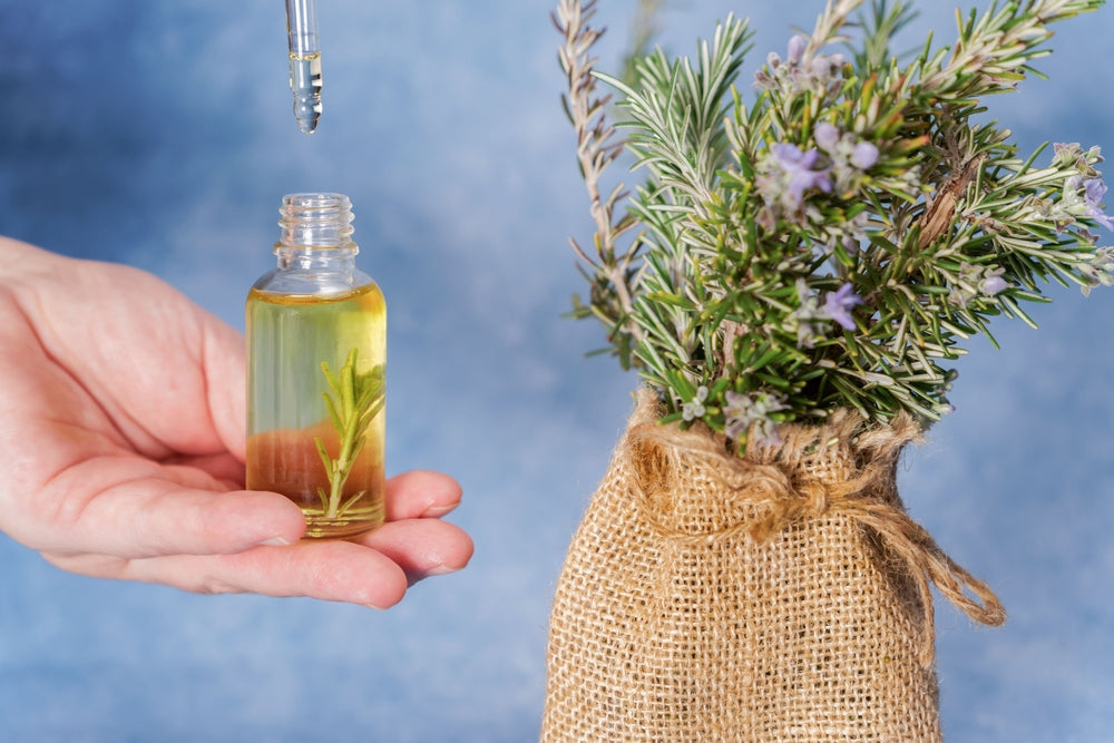 Woman holds a dropper with rosemary essential oil