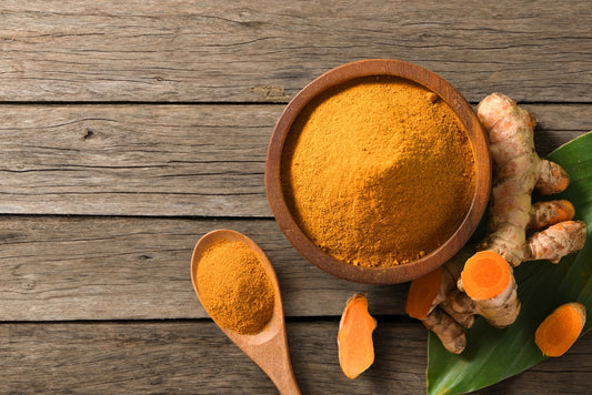 Turmeric (curcumin) powder and fresh rhizome on wooden table.