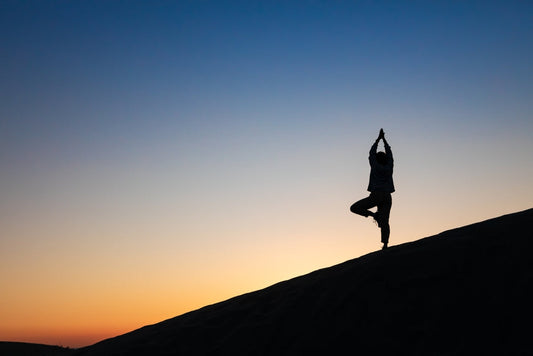 Silhouette of a woman practicing yoga in a balanced 