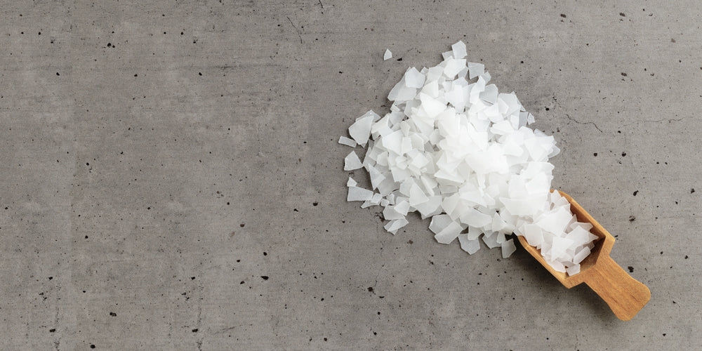 Close-Up of Magnesium Salt Flakes scattered from scoop on grey concrete