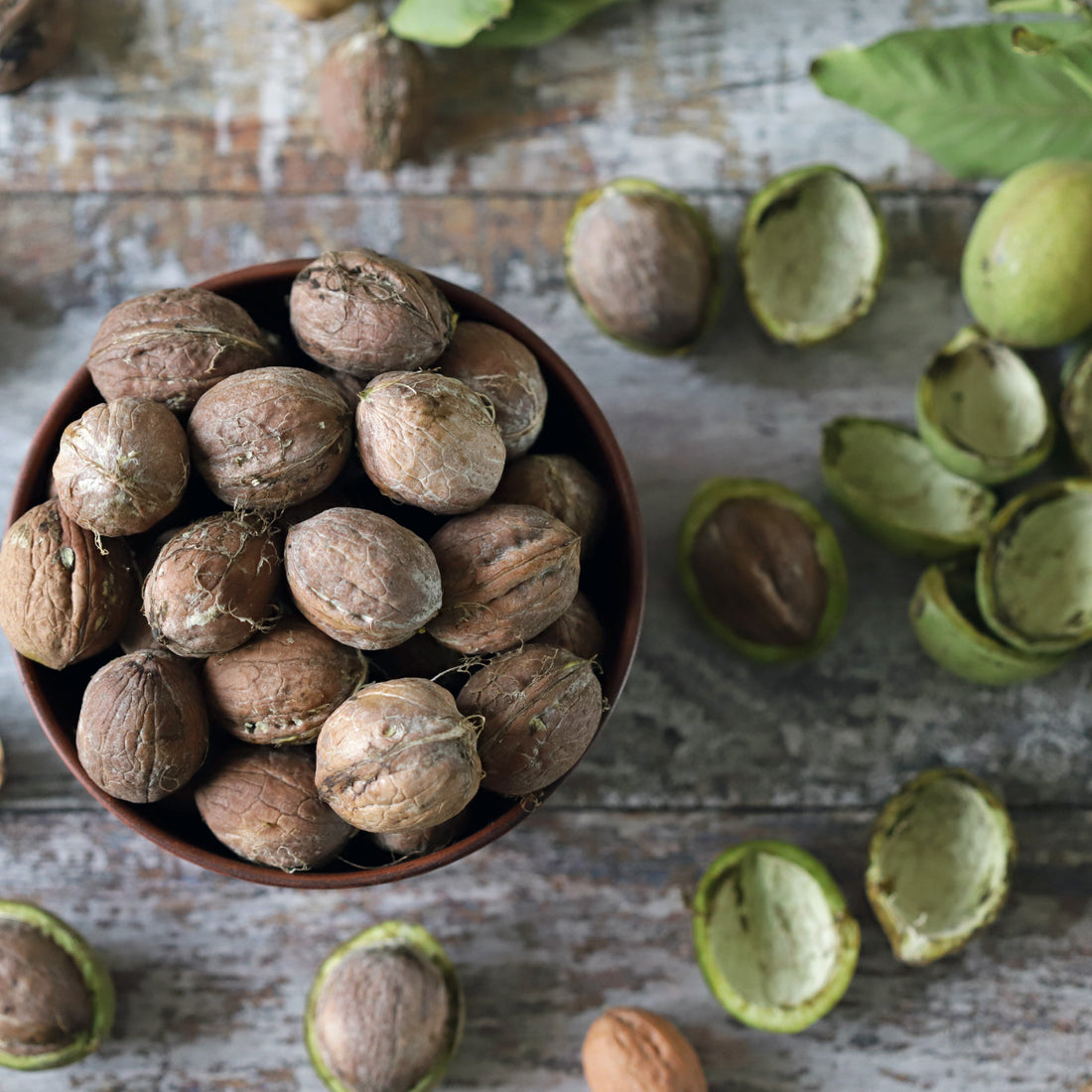 Green Black Walnut Hulls in a Bowl on a Wooden table