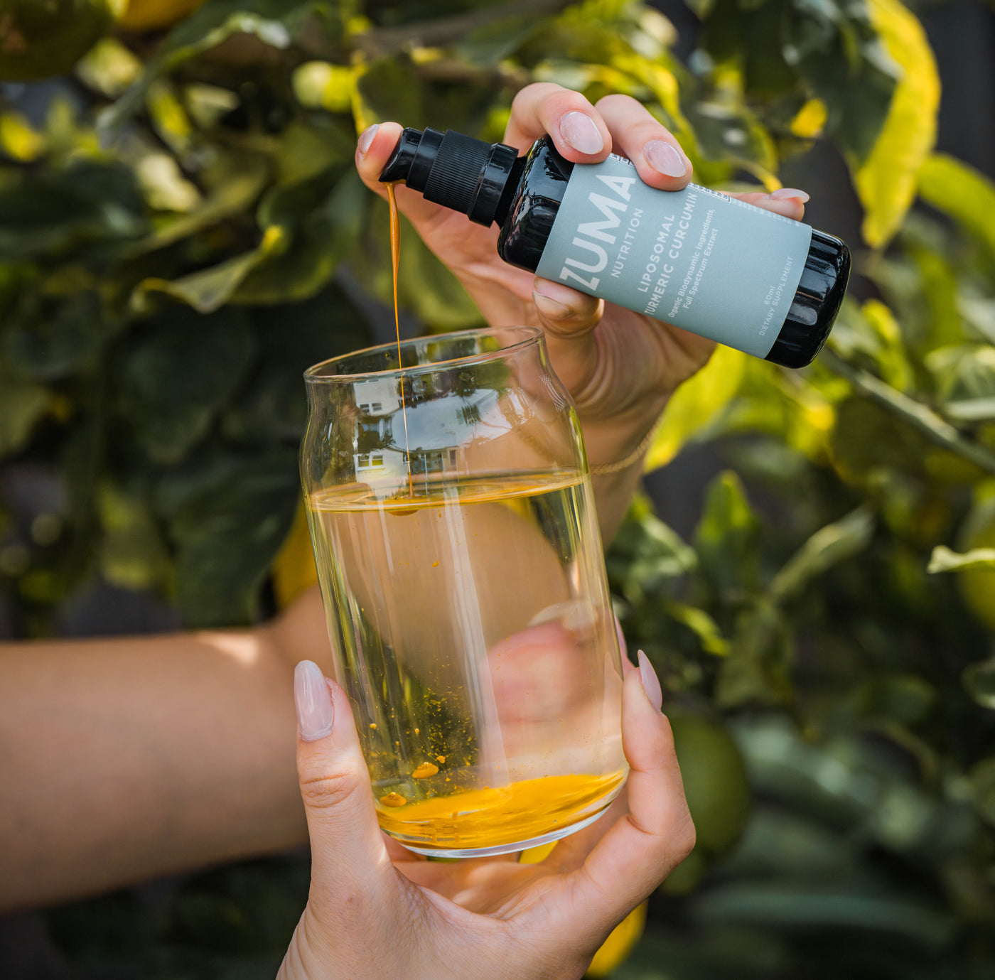 Pouring Liposomal Turmeric Curcumin into a glass of water
